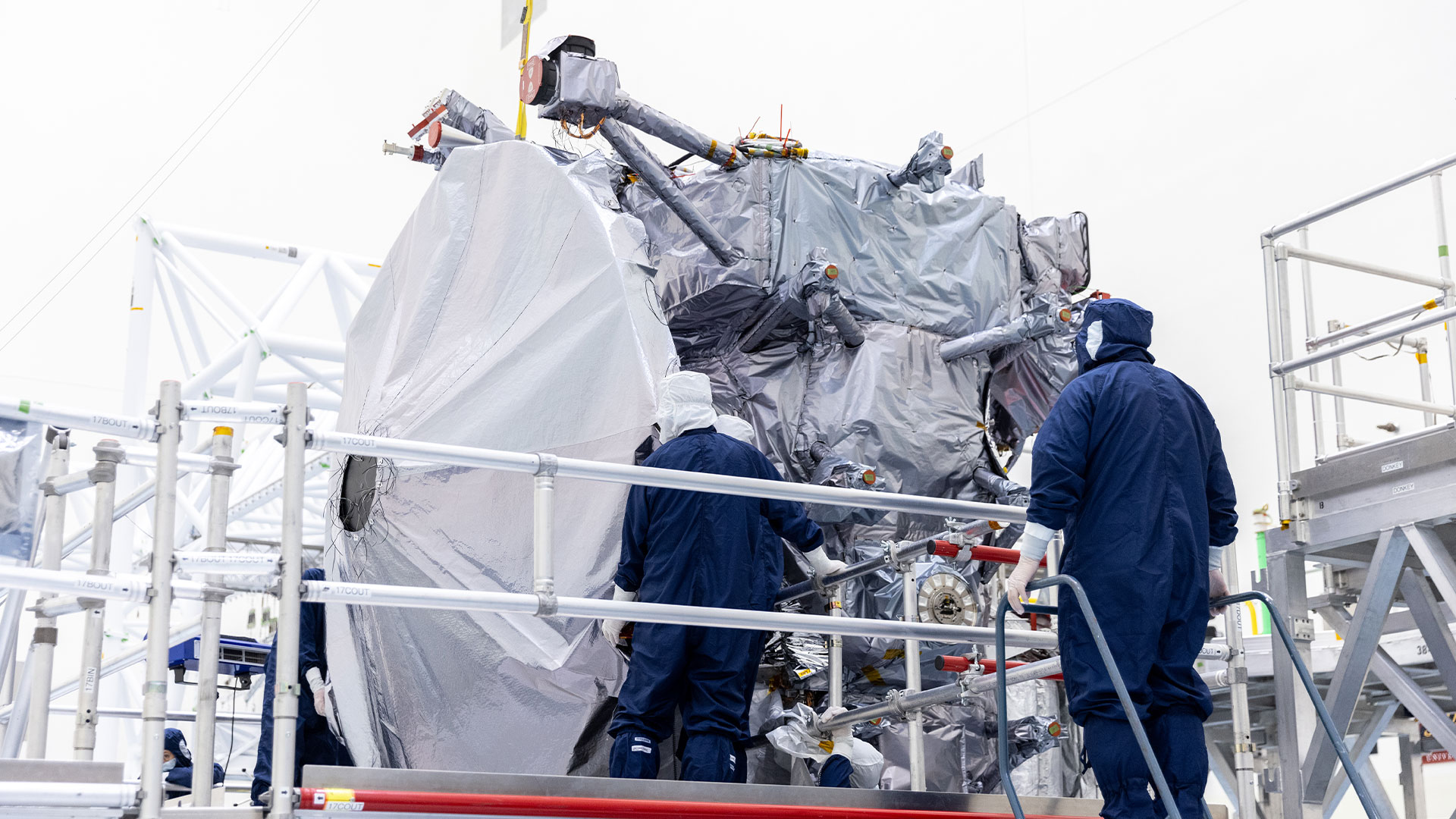 Europa Clipper's high gain antenna sits on a platform surrounded by workers in protective clothing.