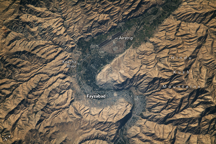 Human settlement evidence is rampant in the river valley that snakes from the bottom center before an S-curve leads out at the top right. The land surrounding this river valley is universally a light brown shade and very mountainous.