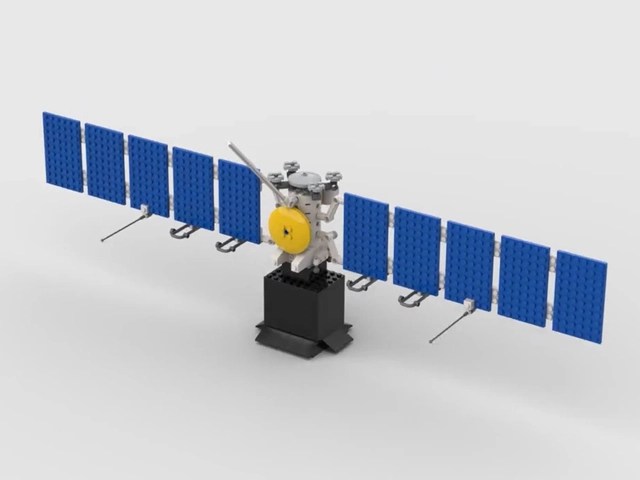 A toy brick model of Europa Clipper with the spacecraft solar arrays in blue, and the high gain antenna in yellow. The rest of the spacecraft is light gray and it's sitting on a black base.